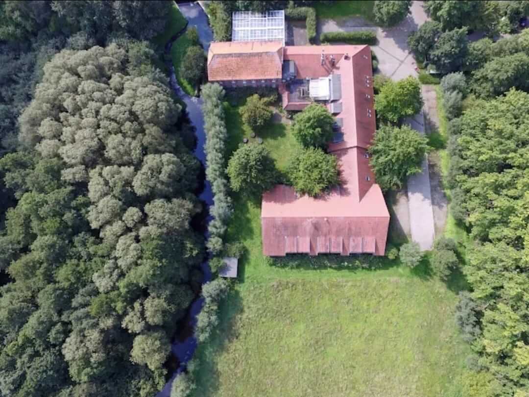 Luftaufnahme des Seminarhauses Leuther Mühle mit Bachlauf und Wald