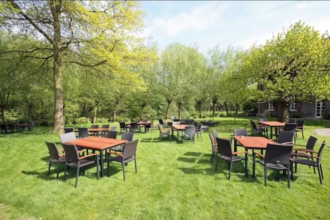 Tische und Stühle im Garten unter Bäumen